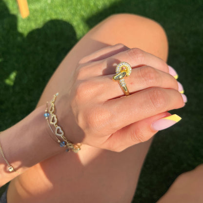 Hand holding Aurora Ring with golden sparkle in sunlight

