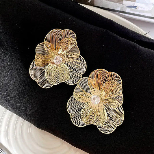 Pair of gold floral earrings on dark cloth – delicate stainless steel studs


